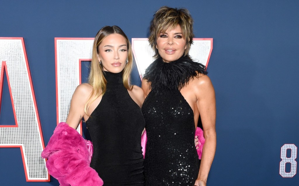 Lisa Rinna and Delilah Belle Hamlin posing in black dresses in front of a navy blue backdrop.