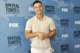 Tyler Cameron wearing white pants and a tan shirt, posing in front of a backdrop for Fox's "Special Forces."