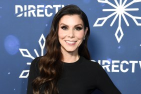 Heather Dubrow smiling and wearing a black dress, standing in front of a blue backdrop with snowflakes