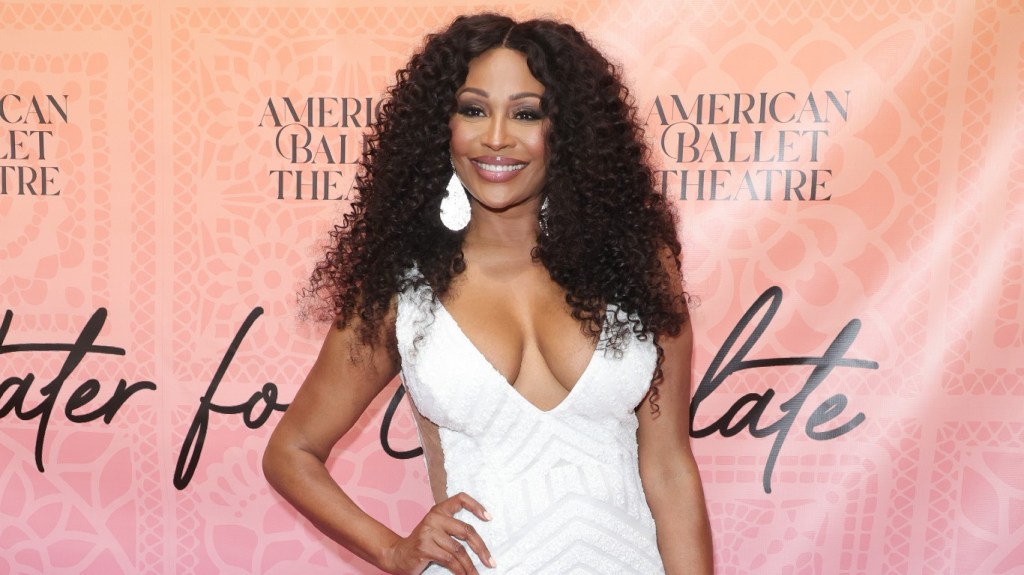 Cynthia Bailey posing in a white dress with her hand on her hip