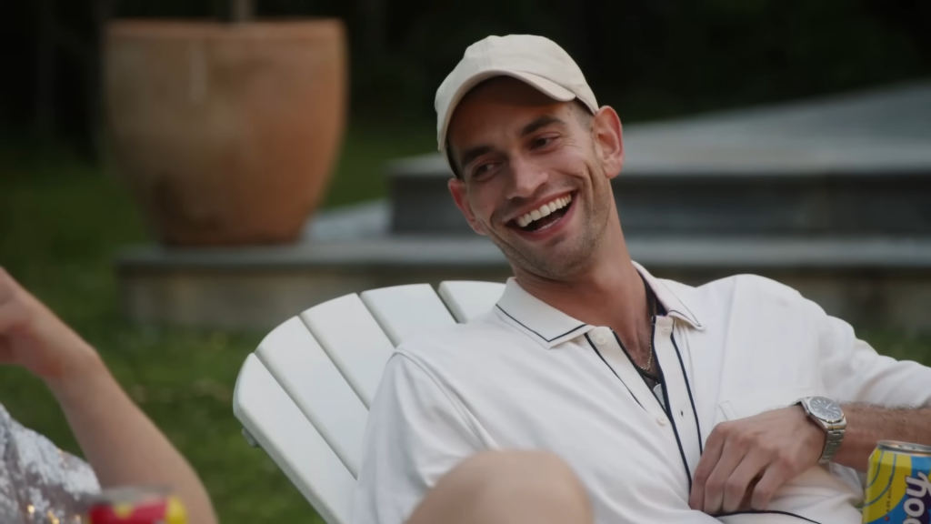 Jesse Soloman grinning and sitting outside in a white chair and wearing an all white outfit on Summer House Season 8