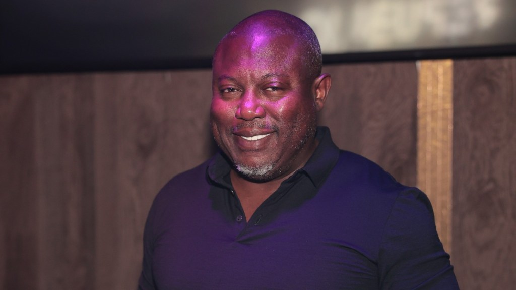 Simon Guobadia smiling and wearing in a navy blue shirt