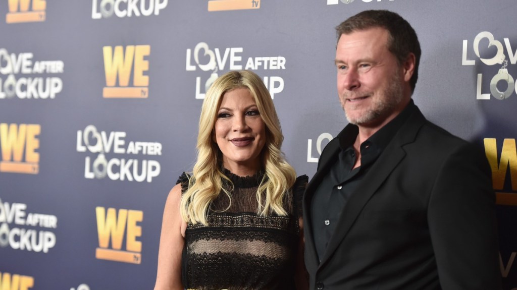 Tori Spelling and Dean McDermott wearing black and posing together on a red carpet