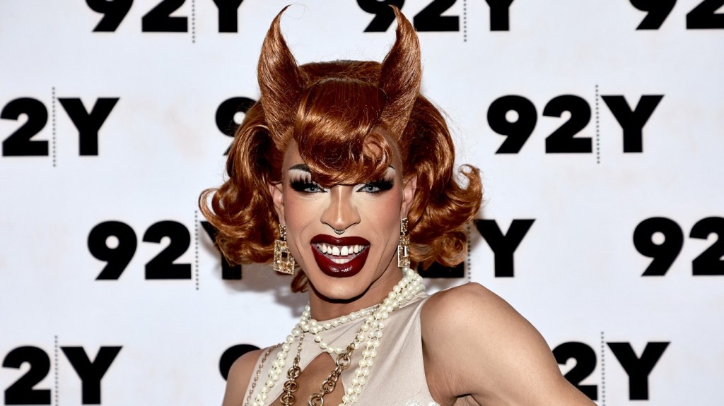 Yvie Oddly in an off-white dress wearing a horn-shaped wig