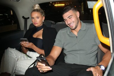 Tommy Fury and Molly-Mae Hague sitting in the back of a car looking at their phones