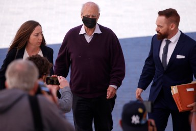 Tom Girardi wearing a mask walking among of group of people to his court hearing