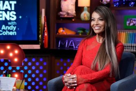 Dolores Catania in a red dress, smiling with her legs crossed on Watch What Happens Live