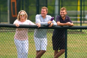 Todd Chrisley and Julie Chrisley standing behind a fence with Chase Chrisley
