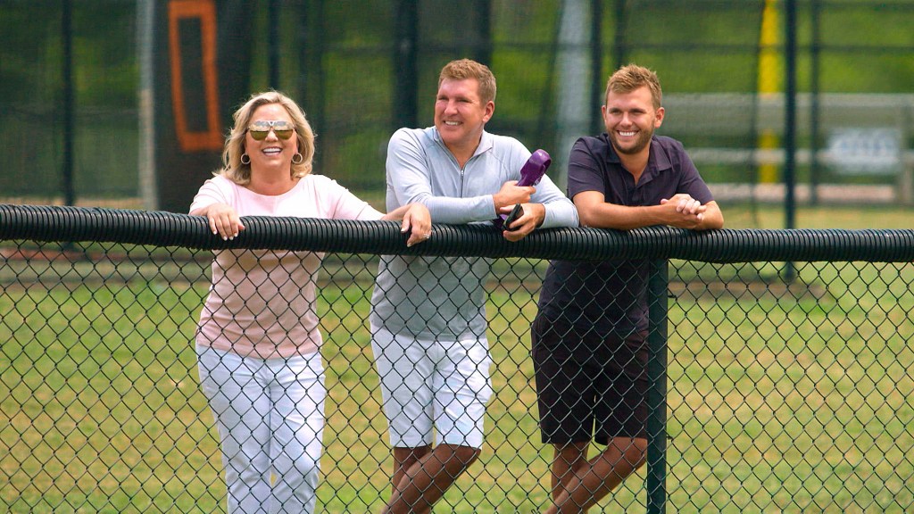 Todd Chrisley and Julie Chrisley standing behind a fence with Chase Chrisley