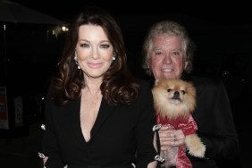 Lisa Vanderpump and Ken Todd wearing all black and holding up a dog wearing a red sweater